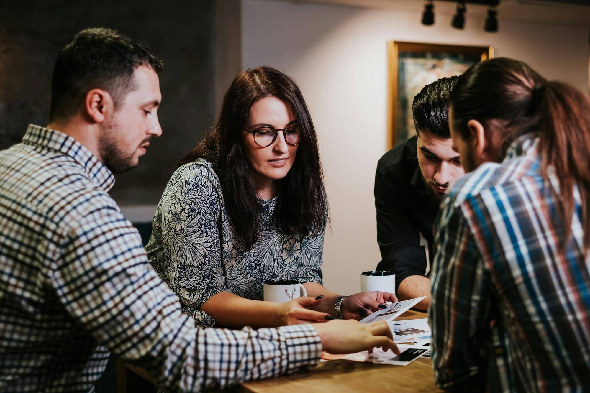 Four people going through paperwork together at a wooden table